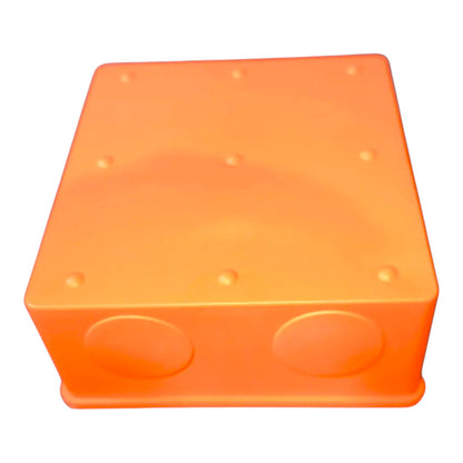 An orange plastic junction box with two circular entry ports on the front face and small raised dots on the top surface, shown against a plain white background.