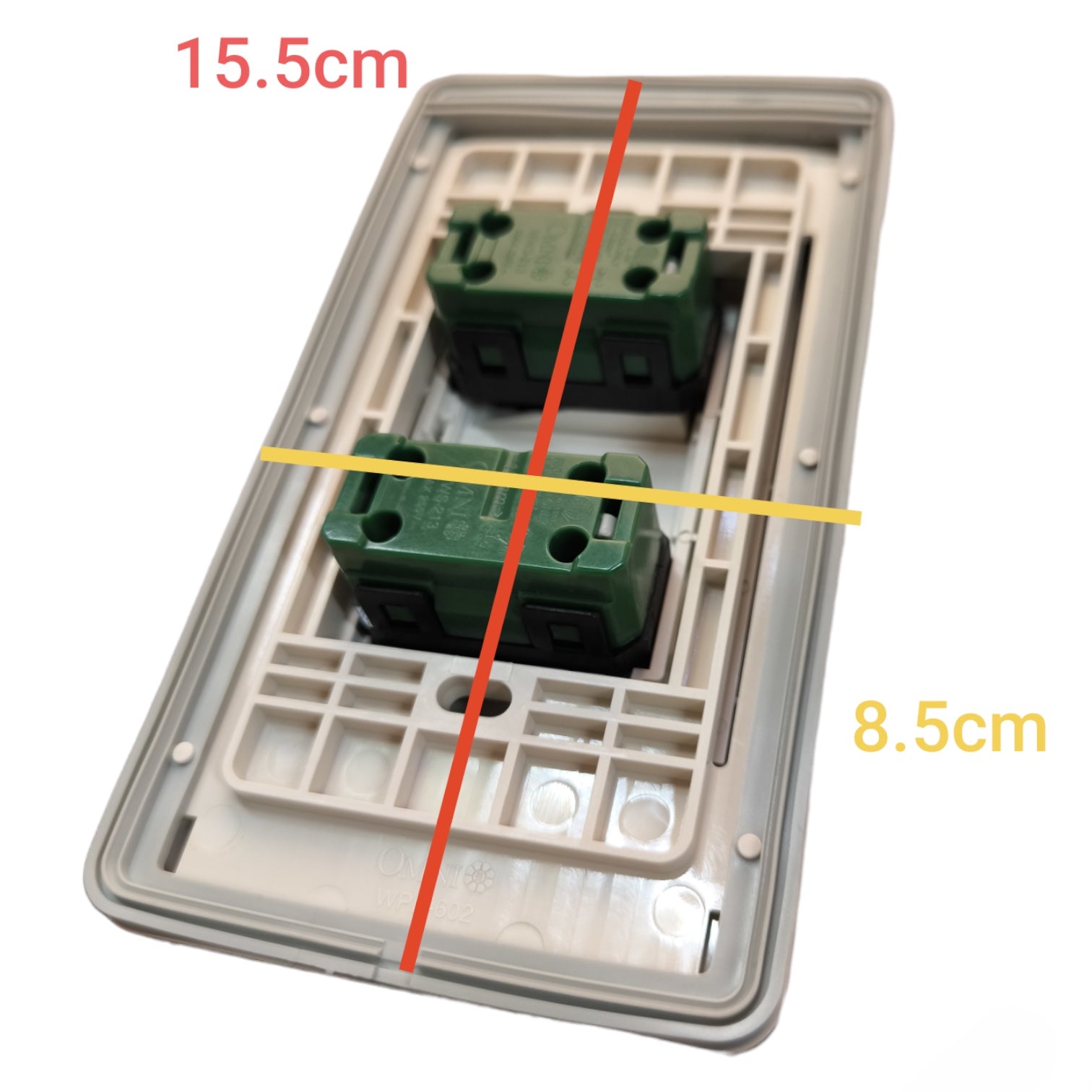 A double-gang wall switch plate with two green terminal blocks, overlaid with red and yellow measurement lines and text showing dimensions 15.5cm and 8.