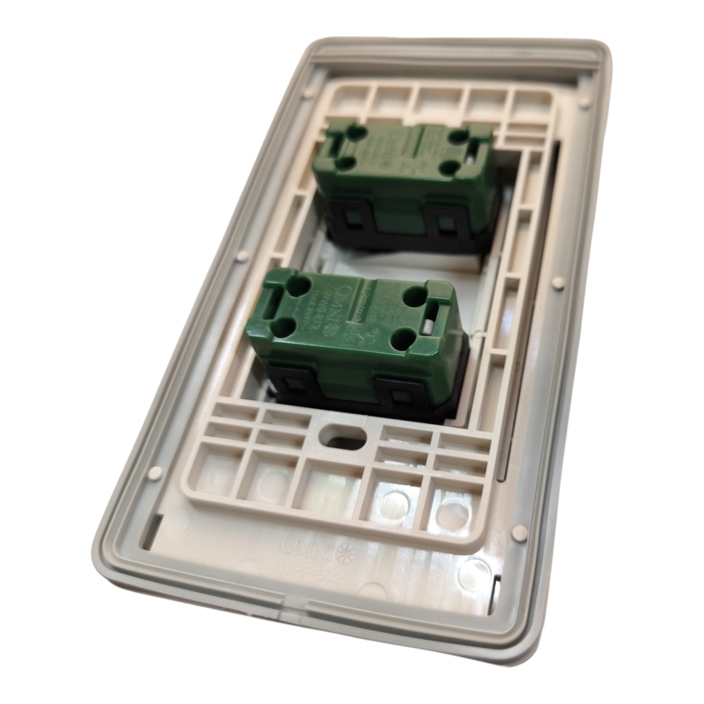 A double-gang electrical switch plate cover with two green terminal blocks set into a beige plastic backplate, shown on a white background.