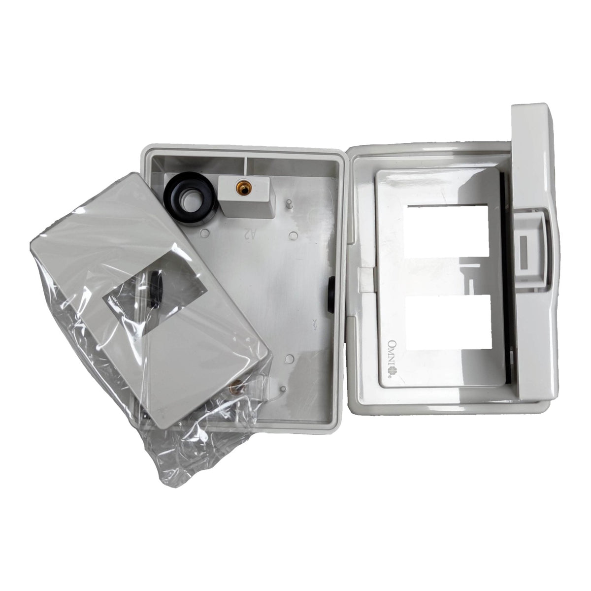 A white plastic electrical junction box or enclosure shown open on a white background, with a separate clear plastic-wrapped component placed beside it. The inside of the box is visible and appears empty or partially assembled.