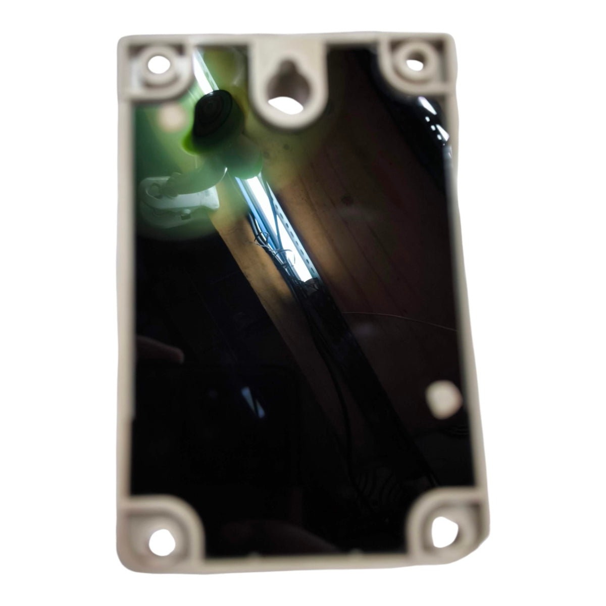 A rectangular black plastic frame or cover with four corner screw holes and a central hanging hole, shown against a white background. The reflective surface inside reflects a room interior with a light source.