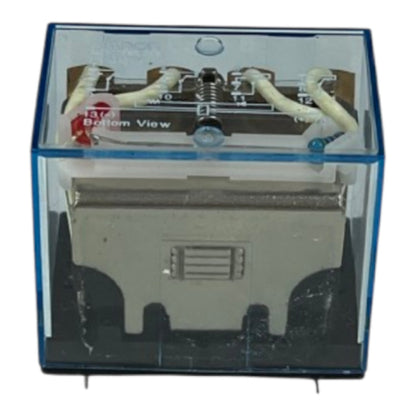 A small electronic component or relay module shown from the bottom view inside a transparent blue protective case, with white wires connected at the top and a gray metal body inside.