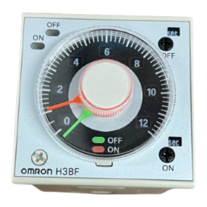 An Omron H3BF analog timer switch with a silver faceplate, black dial, white center knob, and red and green indicator needles.
