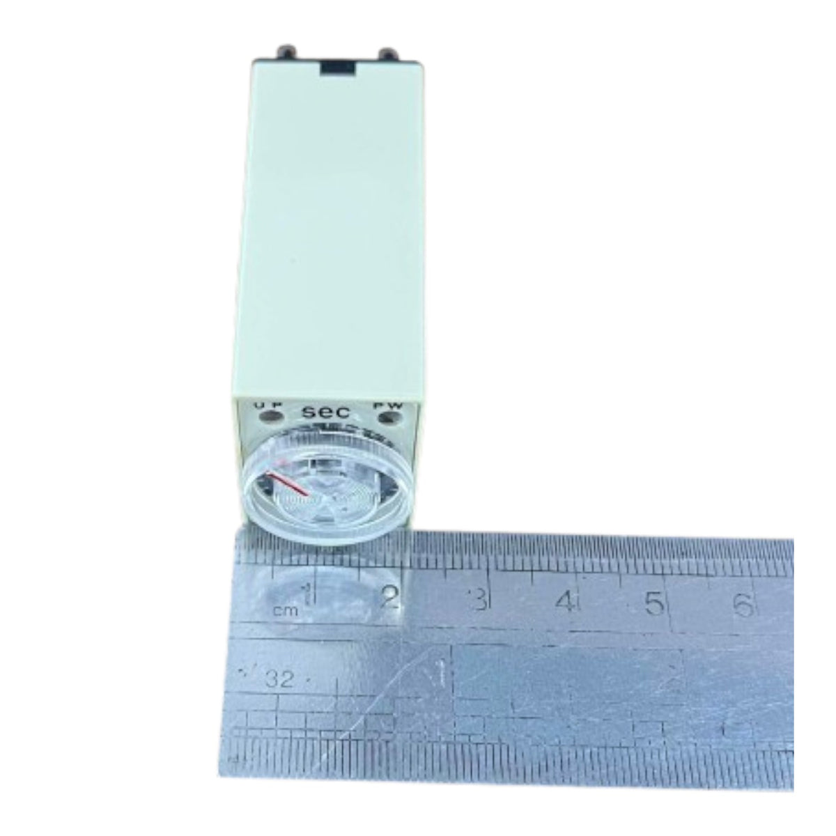 A small rectangular electronic device with a clear circular front window and printed markings including '10 V', '500 mA', 'SEC', and 'PW', shown next to a metal ruler for scale on a white background.