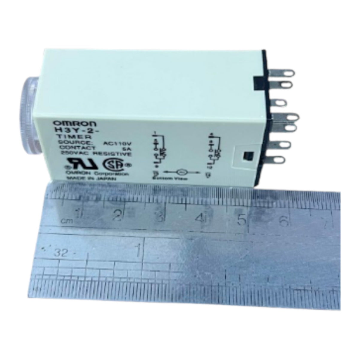 An Omron H3Y-2 timer relay module with a light greenish-gray plastic housing, shown next to a metal ruler for scale on a white background.