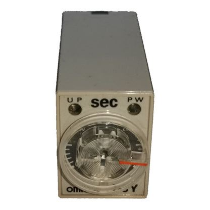 An industrial analog timer relay with a gray metal housing, featuring a circular dial with a clear cover, a red pointer needle, and terminal labels 'UP', 'sec', and 'PW'.