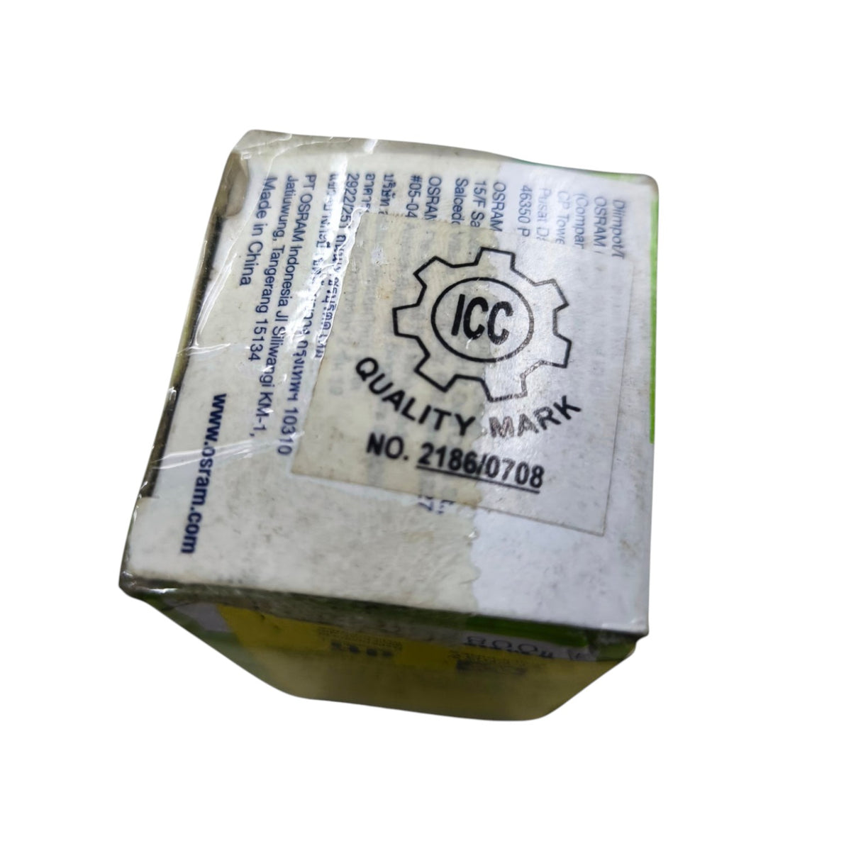 A small rectangular product box wrapped in clear tape, showing a large white label with an ICC Quality Mark logo and printed text, photographed on a plain white background.