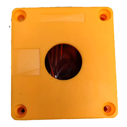 A square orange plastic component with four pre-drilled screw holes in the corners and a circular cutout in the center, showing dark internal wiring or channels. A small rectangular label area is visible on the top side.