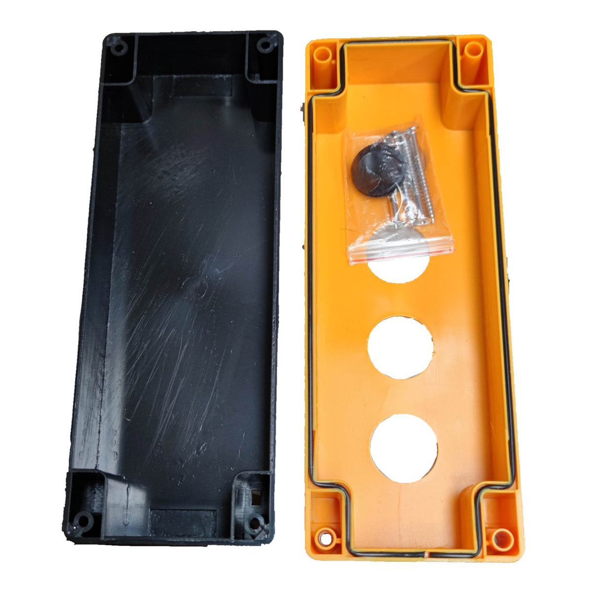 Two plastic electrical junction boxes shown side by side on a white background, one black and one orange, with a small hardware bag containing screws and washers inside the orange box.