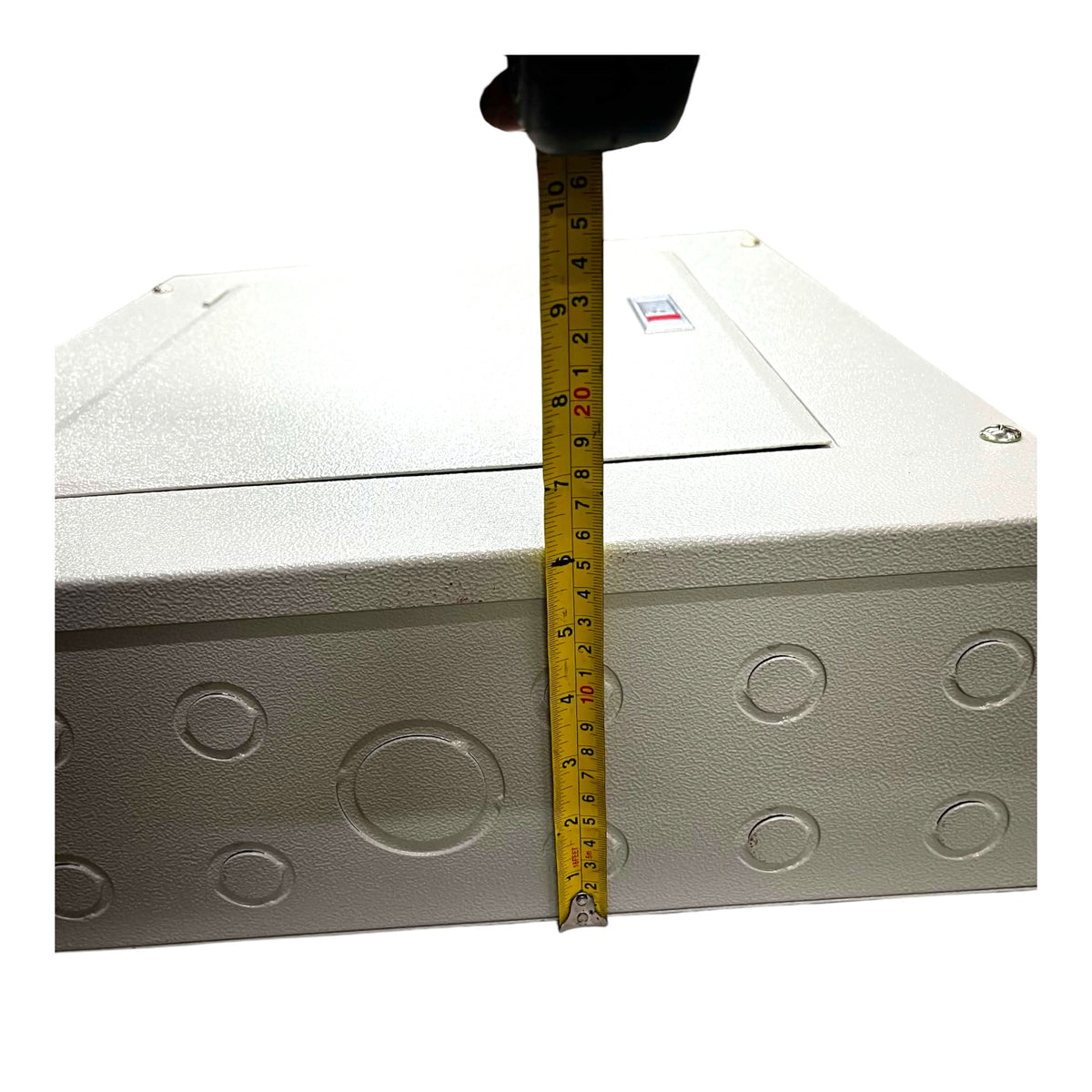 A white metal electrical junction box with circular conduit penetrations, shown with a yellow tape measure standing vertically to indicate its height against a plain white background.