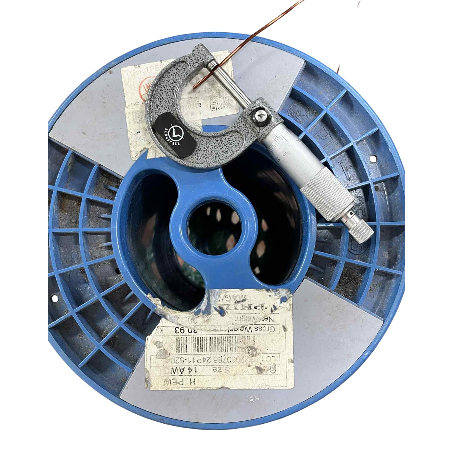 Blue spool with a micrometer on top against a white background
