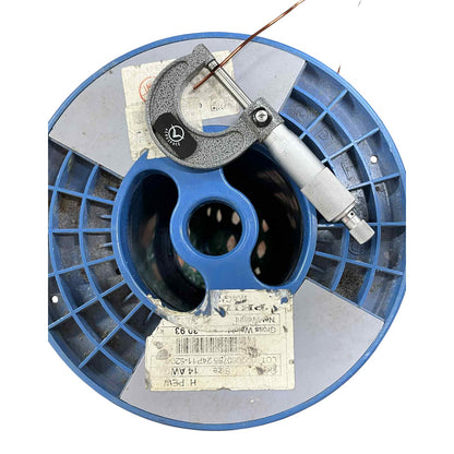 Blue spool with a micrometer on top against a white background