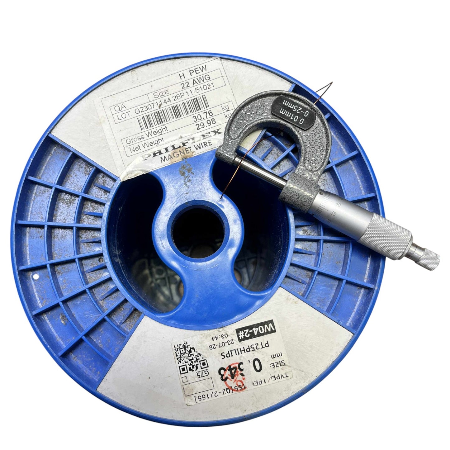 Blue spool of wire with a digital caliper on a white background