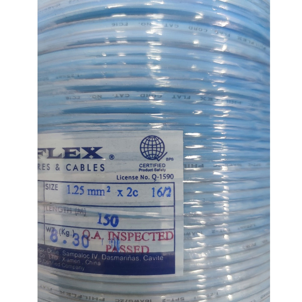 A close-up of a spool of light blue flat cable with a white and blue label showing product details and certification marks.