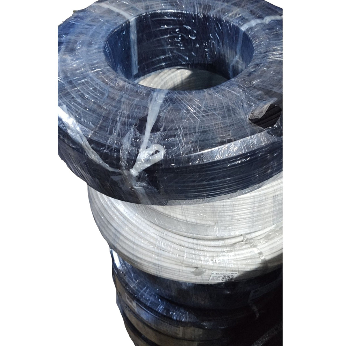 A stack of large industrial wire reels or spools wrapped in clear plastic, with the top reel showing a dark blue-black outer layer and a white inner layer, photographed against a plain white background.