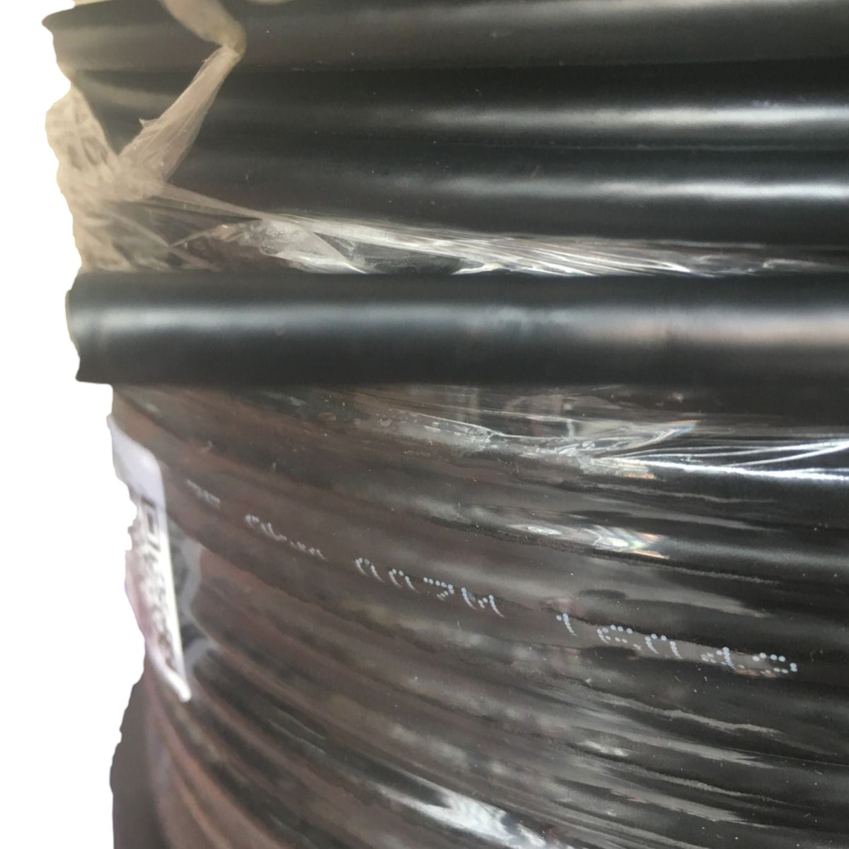 A close-up of a spool of black cable or tubing wrapped in clear plastic, with a white label partially visible on the left side.