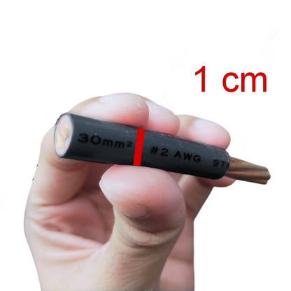 A hand holding a small black cable or wire connector with printed markings including '30mm2', '#2 AWG', and 'ST', with red text in the upper right reading '1 cm' on a plain white background.