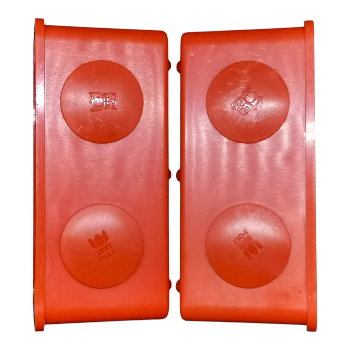 A pair of bright red plastic replacement parts, likely floatation blocks or bumpers, featuring four circular raised sections on each rectangular piece.
