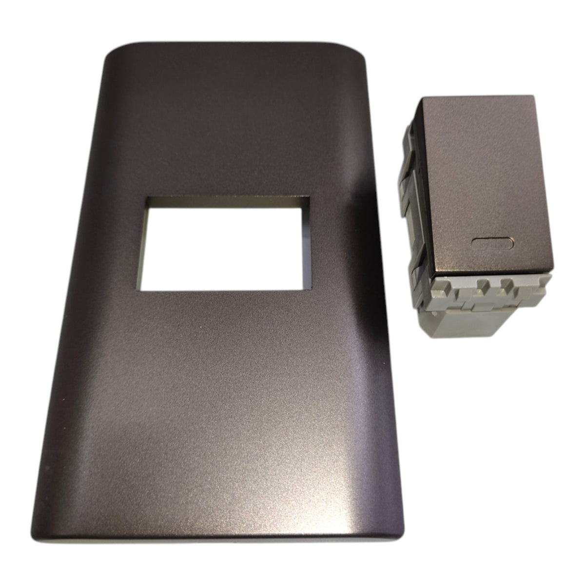 A dark gray rectangular faceplate with a rectangular cutout, shown next to a small matching gray component on a white background.