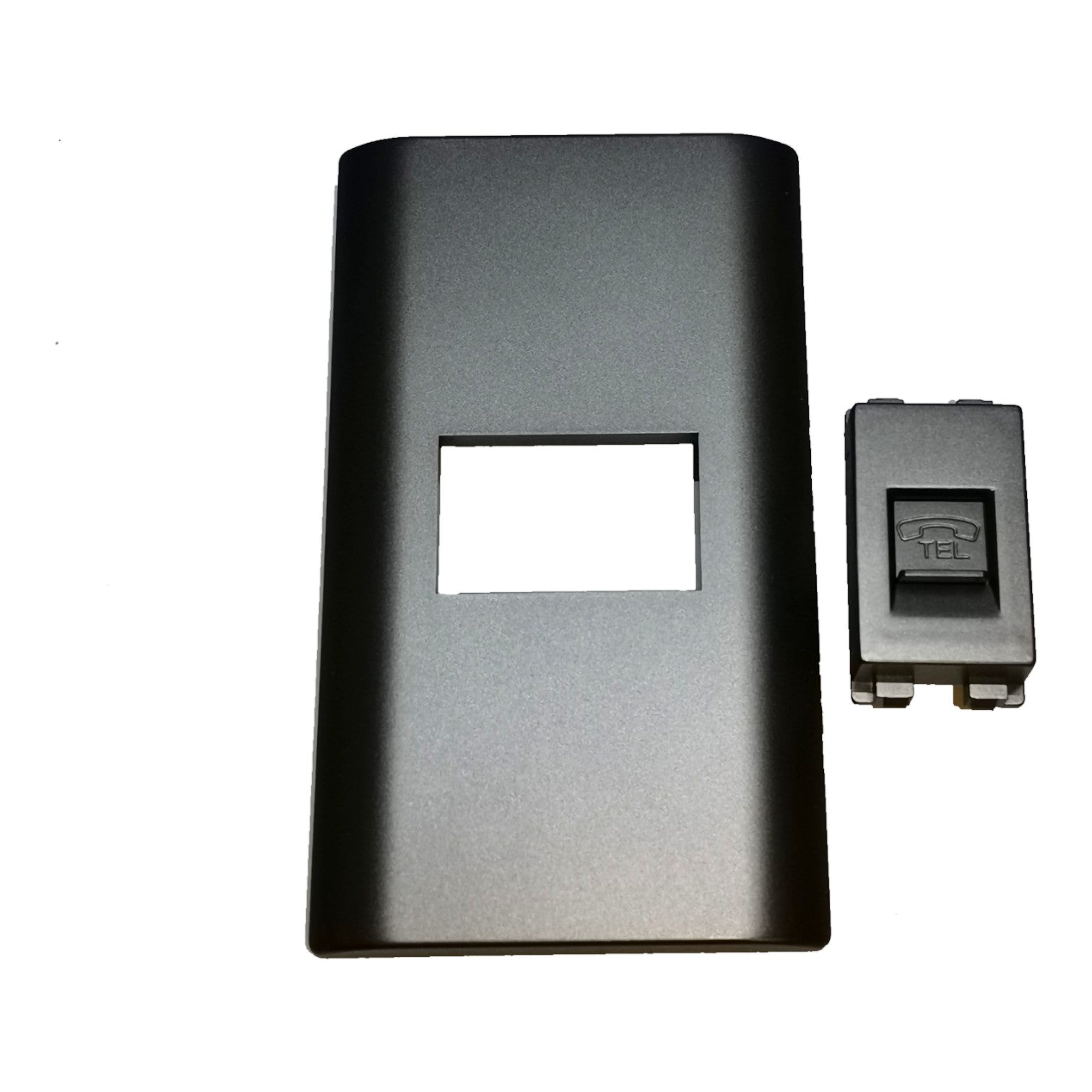 A black rectangular plastic cover with a rectangular cutout in the center, shown alongside a small black switch component on a plain white background.