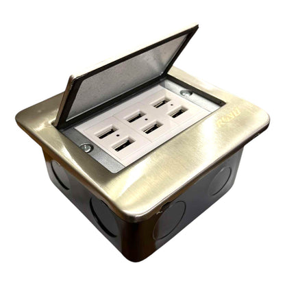 A waterproof outdoor duplex outlet box with a brushed brass top cover that is open, revealing two standard electrical outlets. The box has a black base with circular mounting holes on the front, and the brand name 'KLEER' is embossed on the right side of the brass lid.