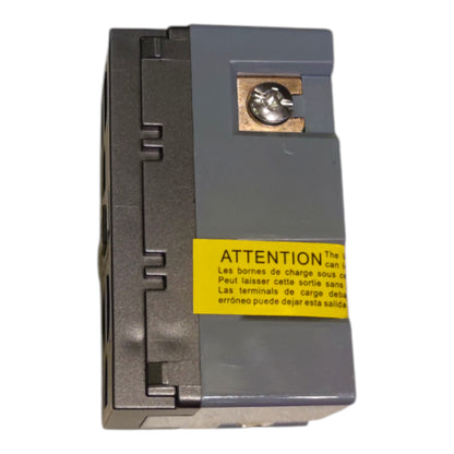 A gray electrical terminal block with a yellow warning label in Spanish and French, featuring a brass screw terminal on the top, isolated on a white background.