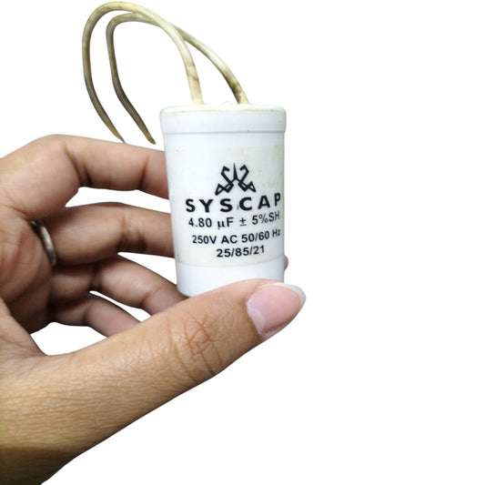 SYSCAP motor capacitor 250V AC held in hand, showing specifications and wires for electrical connection