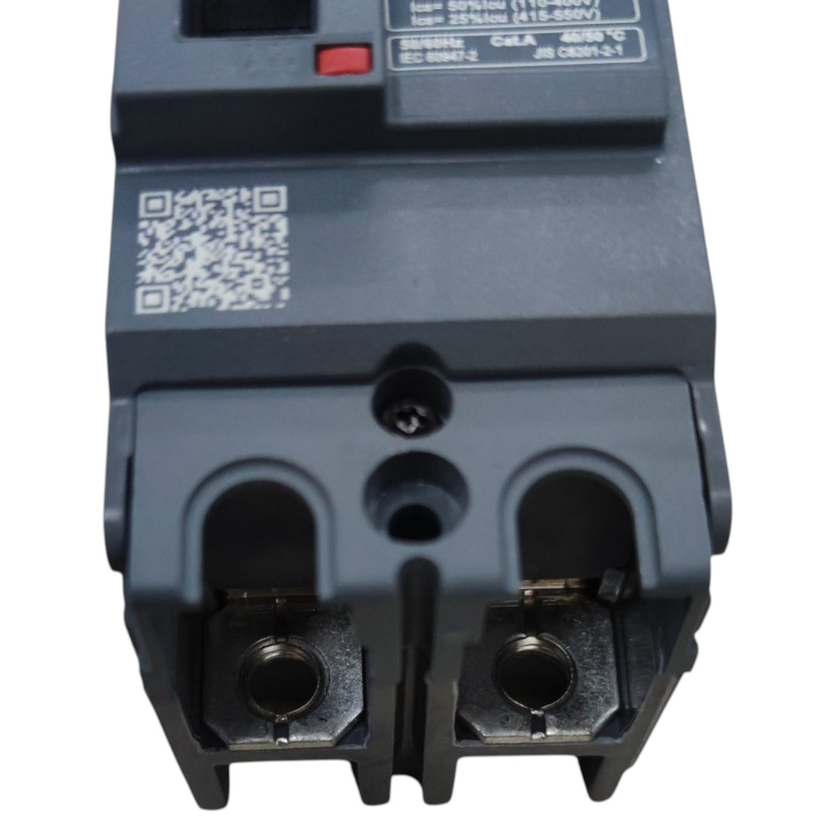 A close-up of a dark gray electrical circuit breaker component with terminal connectors, a QR code, and printed technical specifications on a white background.