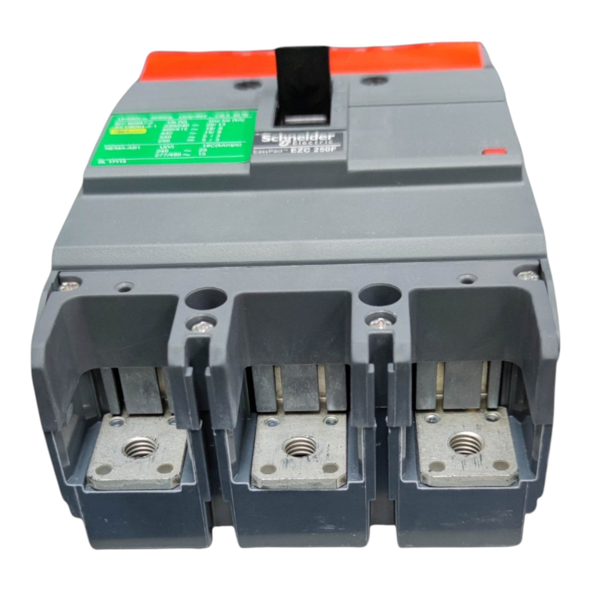 A three-pole circuit breaker with a gray plastic housing, featuring three open terminal compartments, a black handle, an orange top accent, and a green technical specification label.
