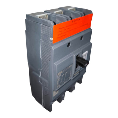 A three-pole circuit breaker with a gray plastic housing, a black switch handle, and a prominent orange caution label on the front.
