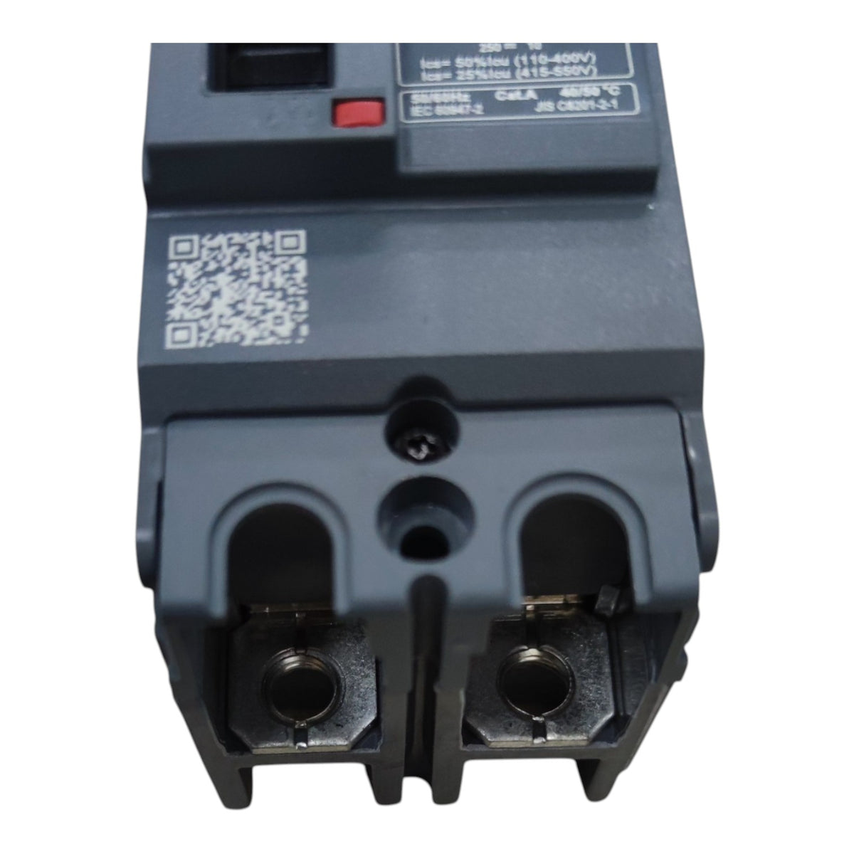 A close-up of a dark gray electrical circuit breaker component with terminal connectors, a QR code label, and printed technical specifications on the top surface, isolated on a white background.