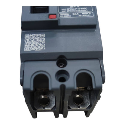 A close-up of a dark gray electrical circuit breaker component with terminal connectors, a QR code label, and printed technical specifications on the top surface, isolated on a white background.