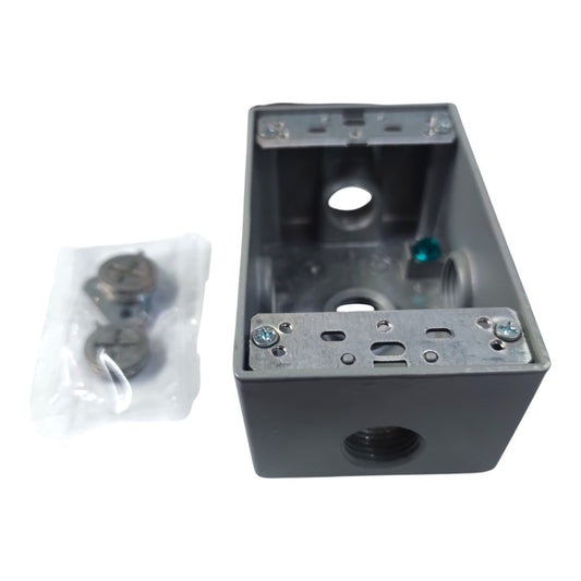 A dark gray metal electrical junction box with a threaded port on the front, shown next to a small clear plastic bag containing mounting hardware, on a white background.