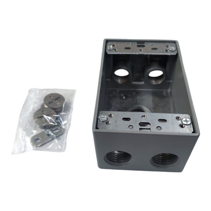A dark gray metal electrical junction box with threaded ports on the front, shown alongside a small clear plastic bag containing mounting screws and washers on a white background.