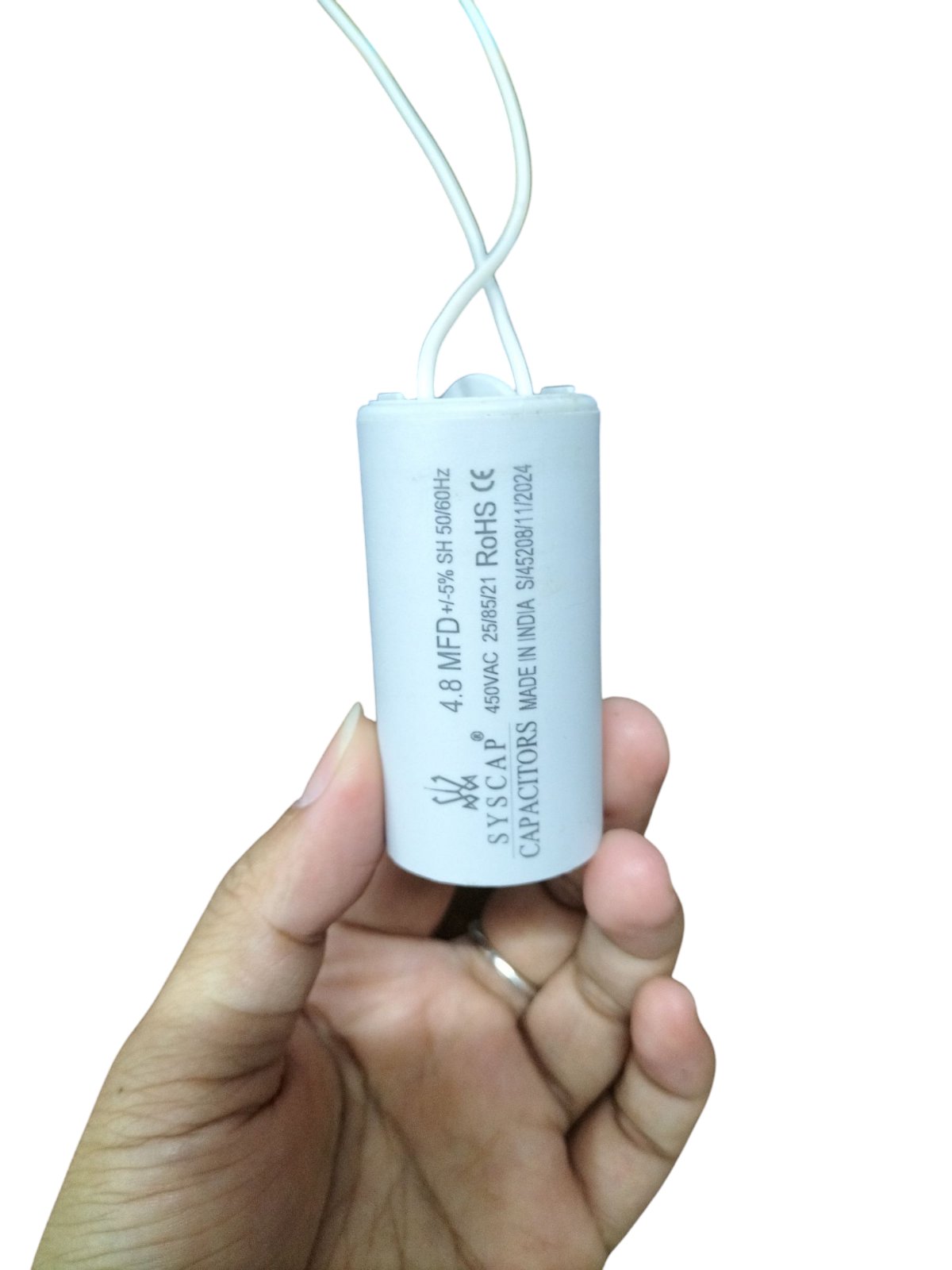Syscap 450VAC capacitor for motors with 4.8 MFD held in hand showing electrical circuitry part