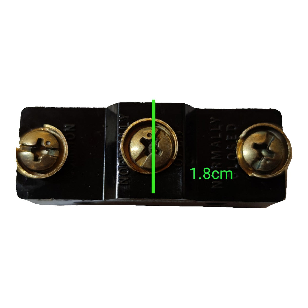 A close-up of a black electrical terminal block with three screw terminals, featuring a green vertical measurement line and text indicating a width of 1.8cm.