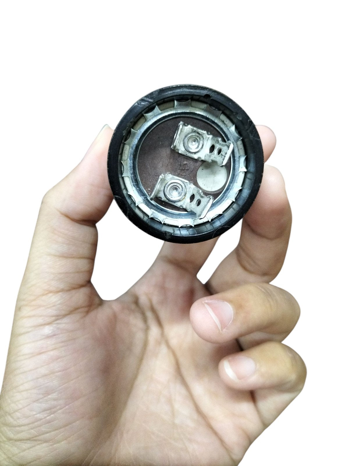 Close-up of a motor start capacitor 125V AC 430-516UF held in hand showing internal circuitry