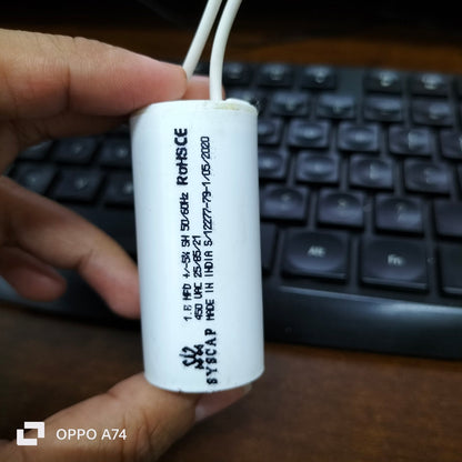 Syscap 1.8MFD 450V AC Motor Running Capacitor held in hand with keyboard background