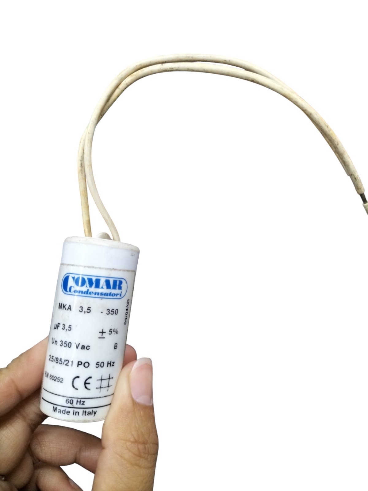 Commar 3.5uF motor run capacitor held in hand with white casing and attached wires