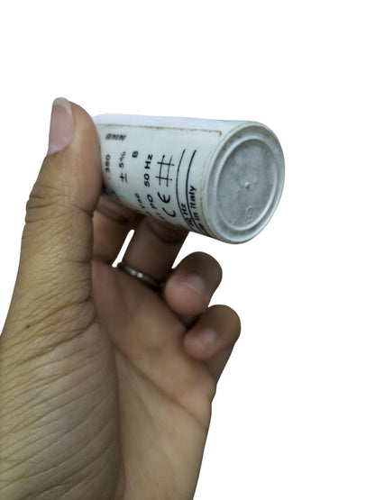Commar 3.5uF motor run capacitor held in hand with white cylindrical body and printed specifications