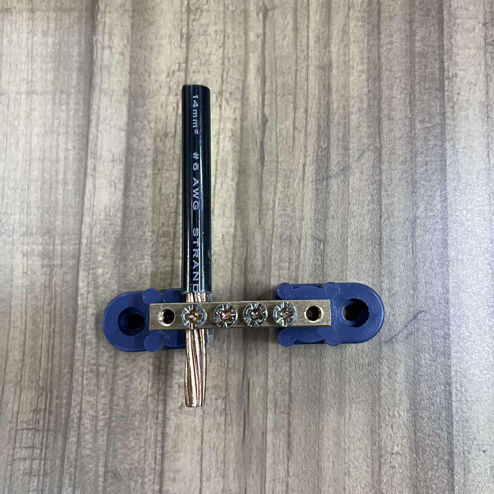 Grippes Electrical Grounding Bus Bars 4 Holes with attached black grounding wire on wood surface