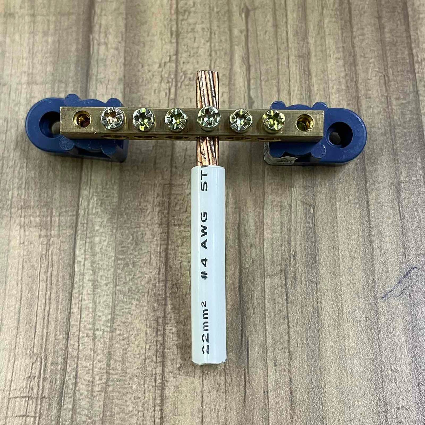 Grippes Grounding Bus Bars 4 Holes with copper wire and blue mounting brackets on wood surface