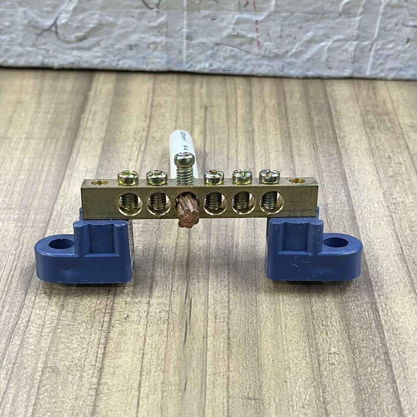 Grippes Grounding Bus Bars 4 Holes electrical part with brass bar and blue mounts on wooden surface
