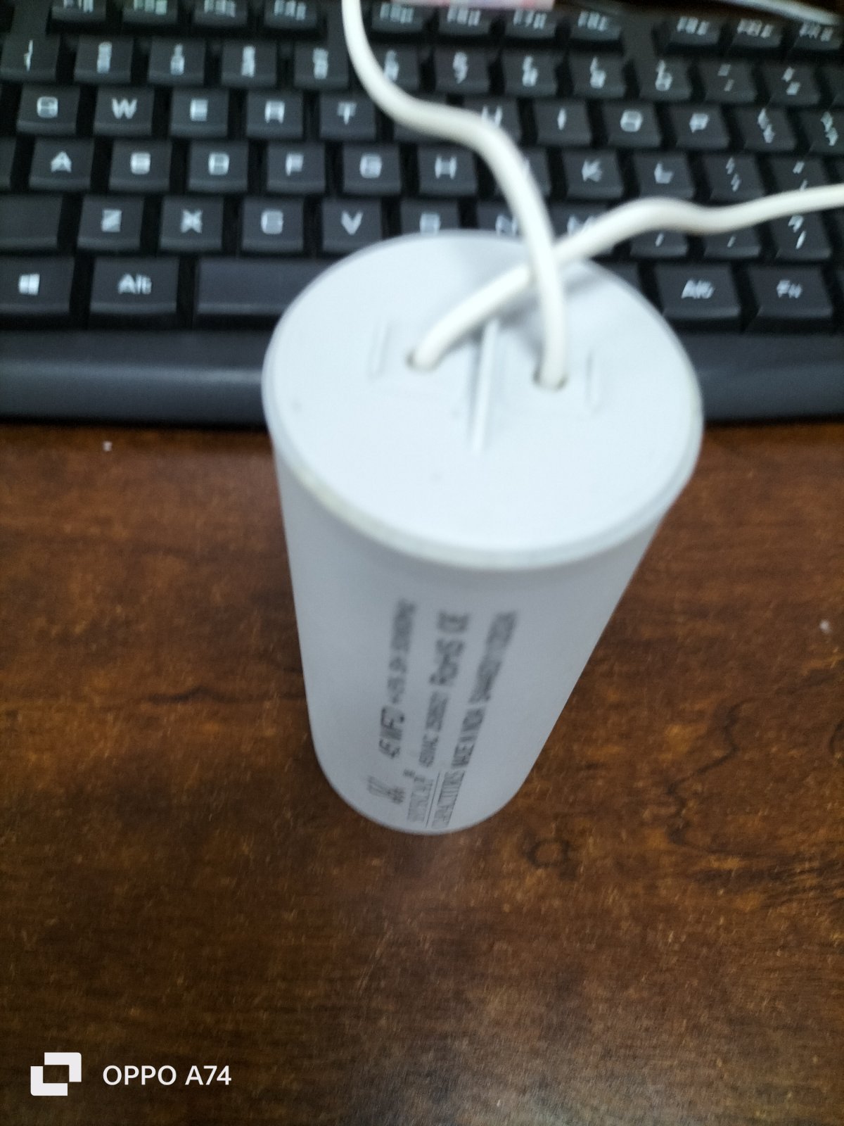 Syscap Motor Capacitor for electrical circuits with two connection wires on a wooden surface