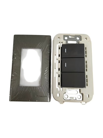 Panasonic 3 gang switch with black rocker panels and separate metallic faceplate in packaging