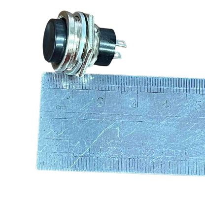 Push Button 1A 220V Black positioned next to a ruler for size reference