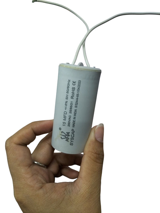 Hand holding Syscap 15MFD 250V AC Running Capacitor electrical circuitry part with two wires