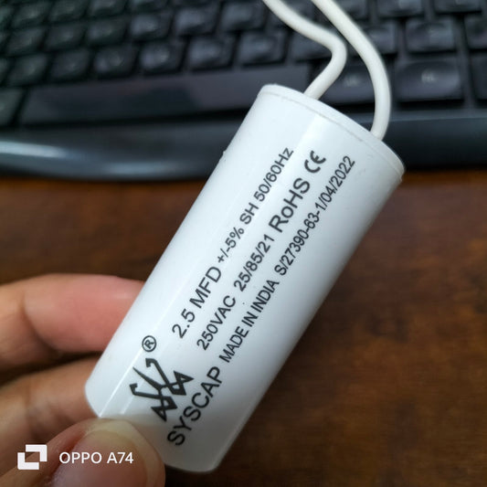 Syscap 2.5MFD motor running capacitor white cylindrical electrical component held by hand