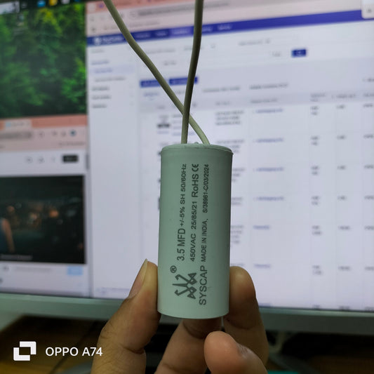 Syscap 3.5MFD 450V AC Running Capacitor held by hand in front of a computer screen