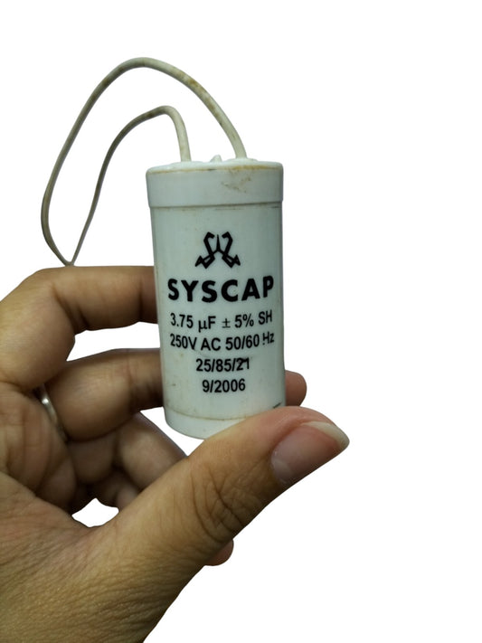 Syscap 3.75uF 250V AC capacitor held between fingers with white cylindrical body and wires